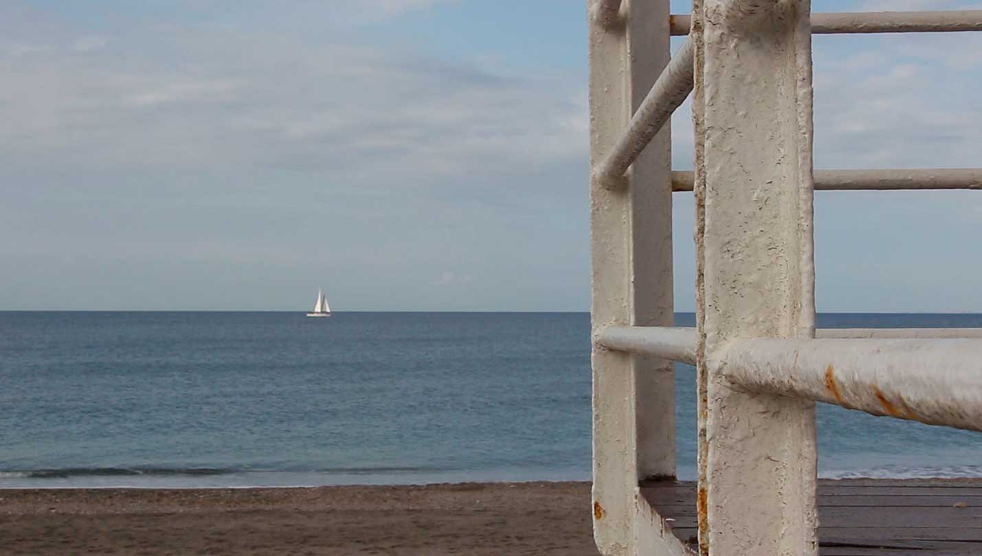 Vista a lo lejos de una embarcación velera navegando por el mar.