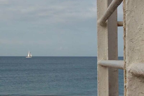 Vista a lo lejos de una embarcación velera navegando por el mar.