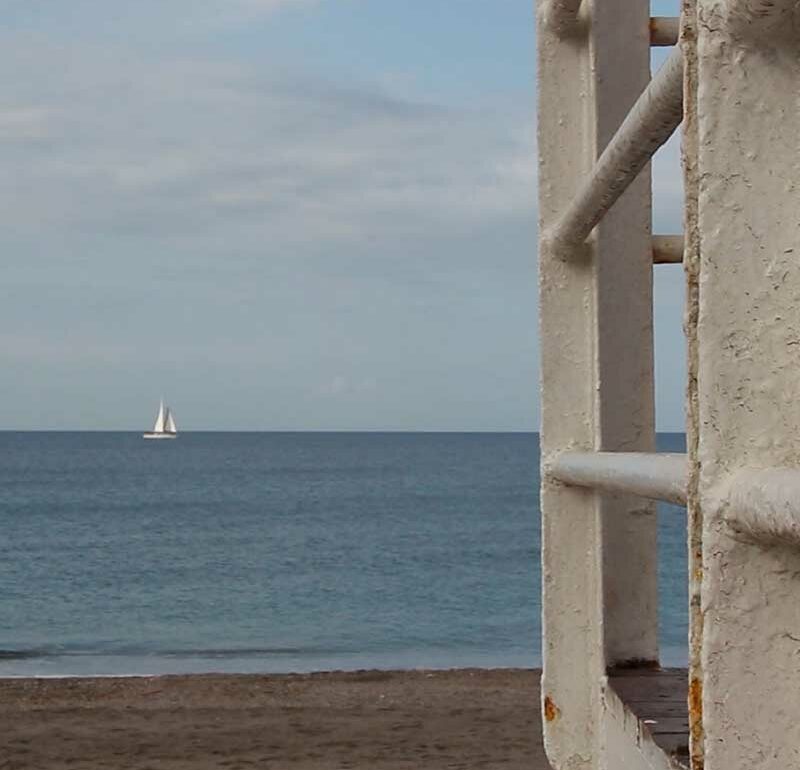 Vista a lo lejos de una embarcación velera navegando por el mar.