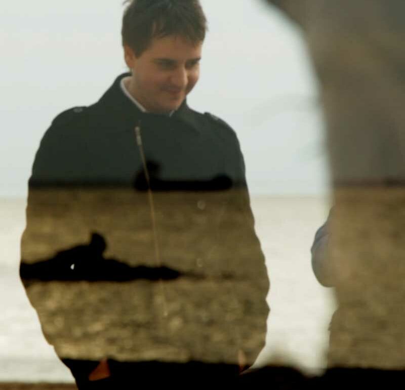 Hombre paseando por la playa con un plano superpuesto del mar, mezclándose las imágenes entre sí.