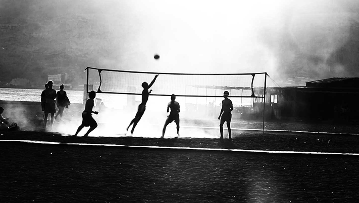 Imagen en blanco y negro de un partido de voleibol en la playa.