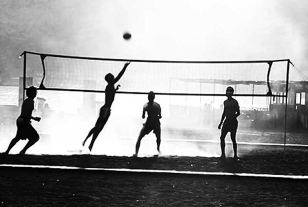 Imagen en blanco y negro de un partido de voleibol en la playa.
