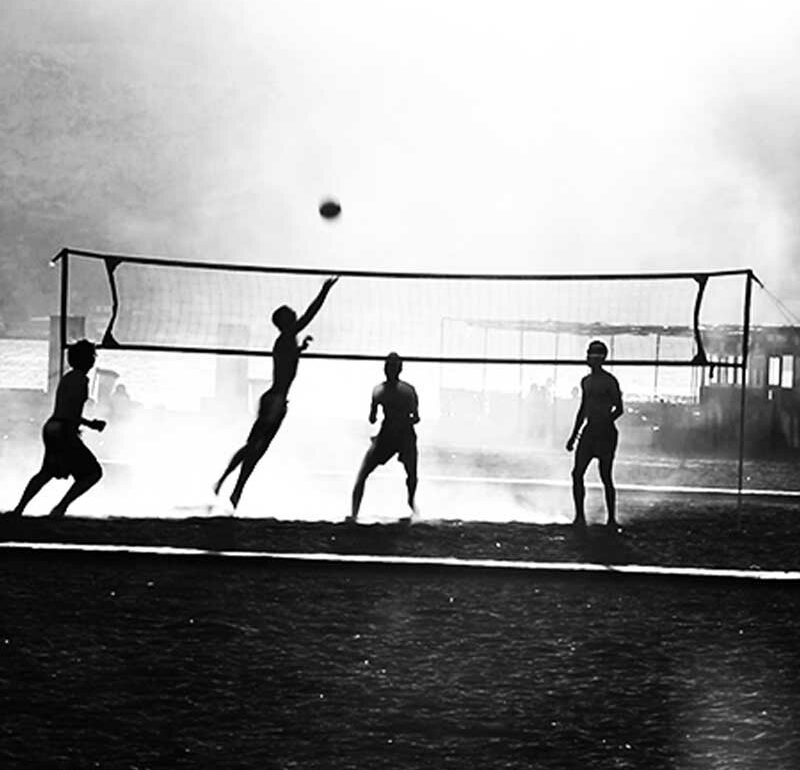 Imagen en blanco y negro de un partido de voleibol en la playa.